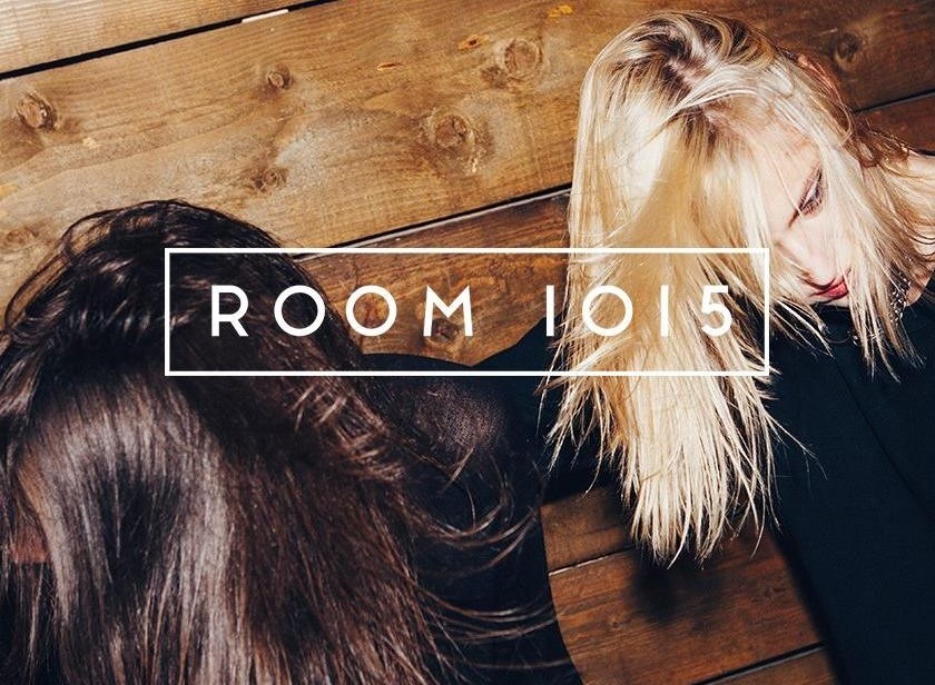 Logo ROOM 1015 i dwoje ludzi na drewnianej podłodze